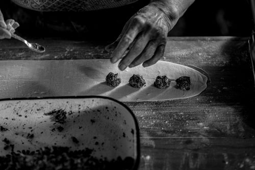 Free A black and white photo capturing hands making dumplings on a floured surface. Stock Photo