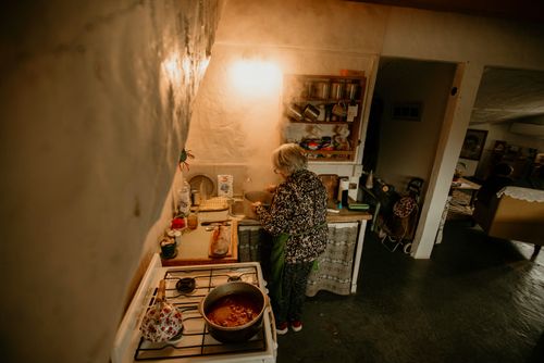 Free An elder woman cooks in a warm, rustic kitchen setting, evoking a sense of home and tradition. Stock Photo