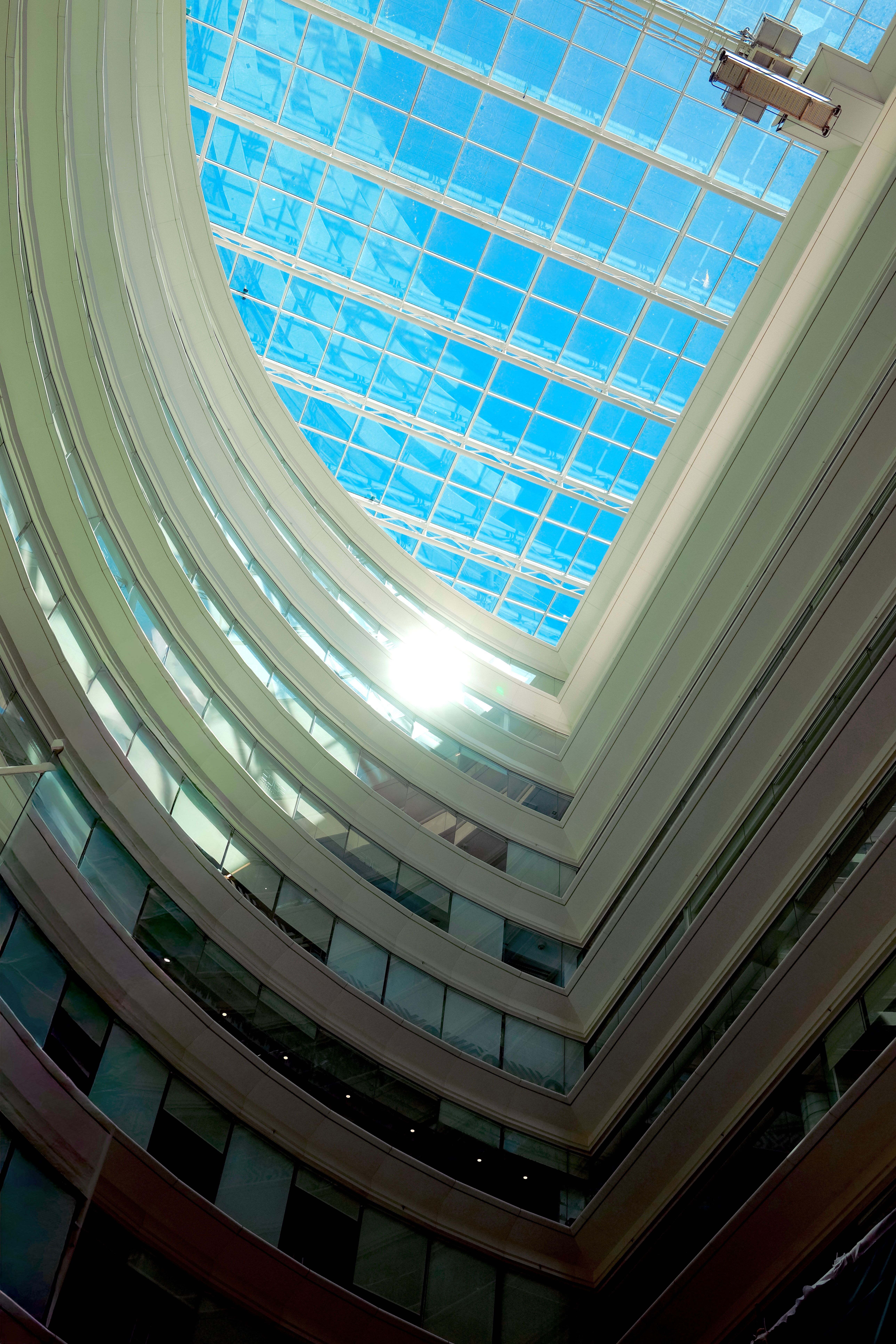 A view of a blue sky through a modern office building atrium skylight.