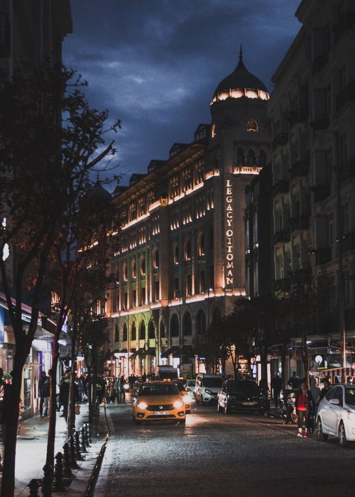 Free Nighttime view of Legacy Ottoman Hotel with bustling street in Istanbul cityscape. Stock Photo