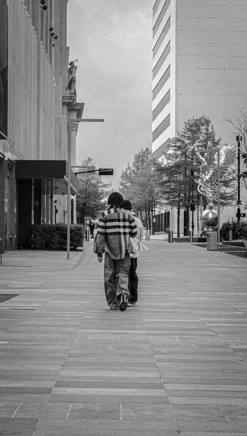 Free Monochromatic urban scene with people walking along a city street, featuring modern architecture. Stock Photo