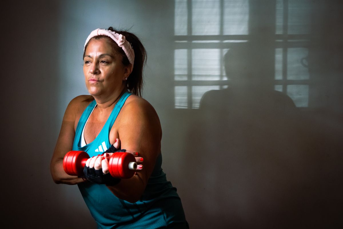 Woman strength training with dumbbells in a home fitness space