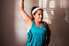 Middle-aged woman lifting a red dumbbell indoors, demonstrating strength and fitness at home.