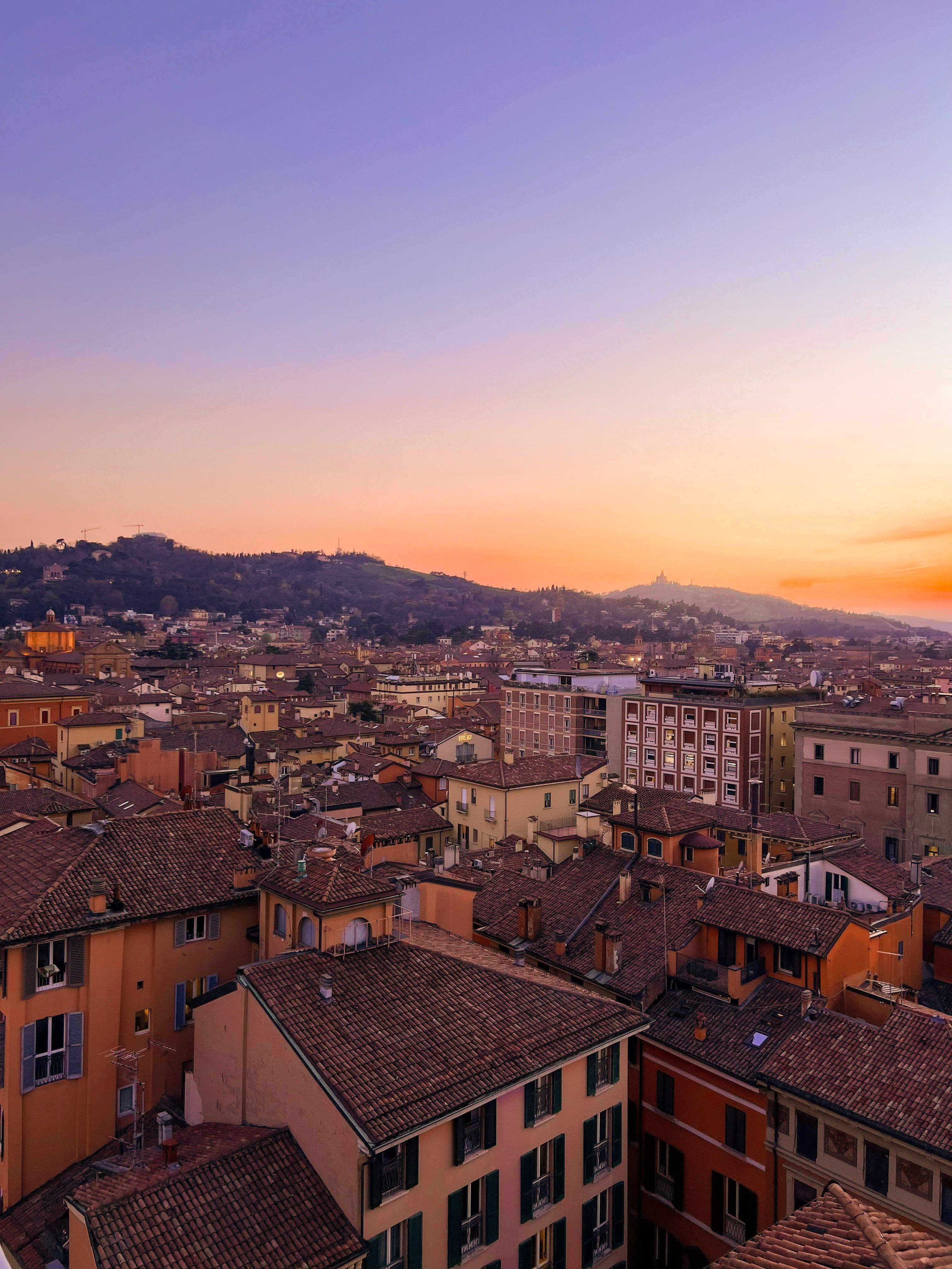 A beautiful aerial view of Bologna's historic rooftops under a serene sunset sky.