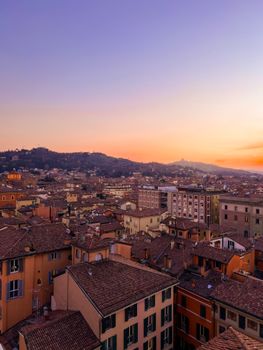 A beautiful aerial view of Bologna's historic rooftops under a serene sunset sky.