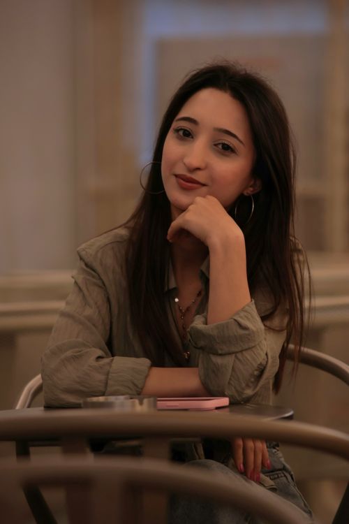 Free A relaxed portrait of a young woman sitting at a cafe table indoors. Stock Photo