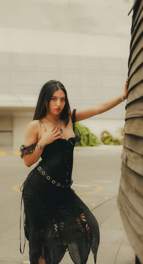 Free Portrait of a stylish woman in black dress posing outdoors with an urban backdrop. Stock Photo