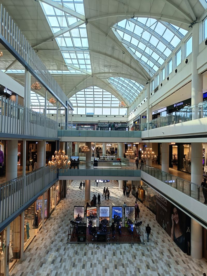 A bright, spacious shopping mall with high skylights and multiple levels, bustling with shoppers.