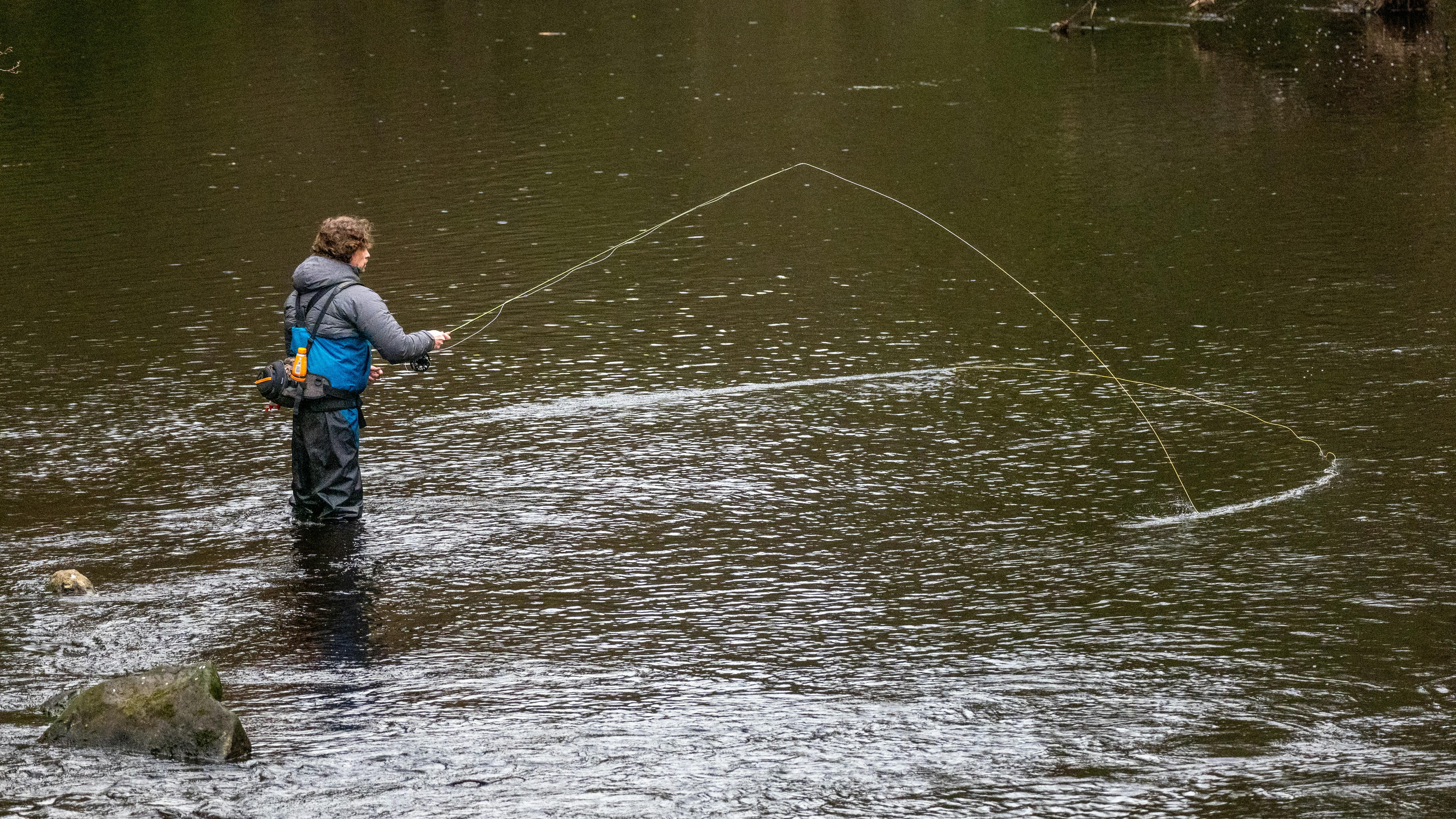 Man fly fishing in River Nidd, Knaresborough, UK, showcasing angling skills.
