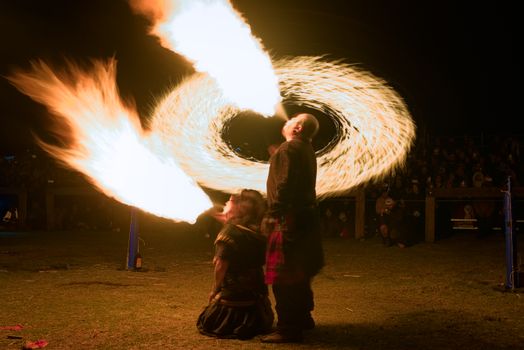 Exciting night fire breathing show with dynamic flames captivating the audience.