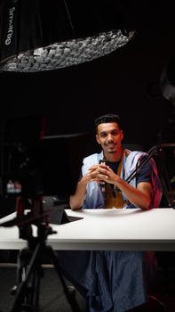 Smiling man posing in a professional studio setting with lighting equipment.