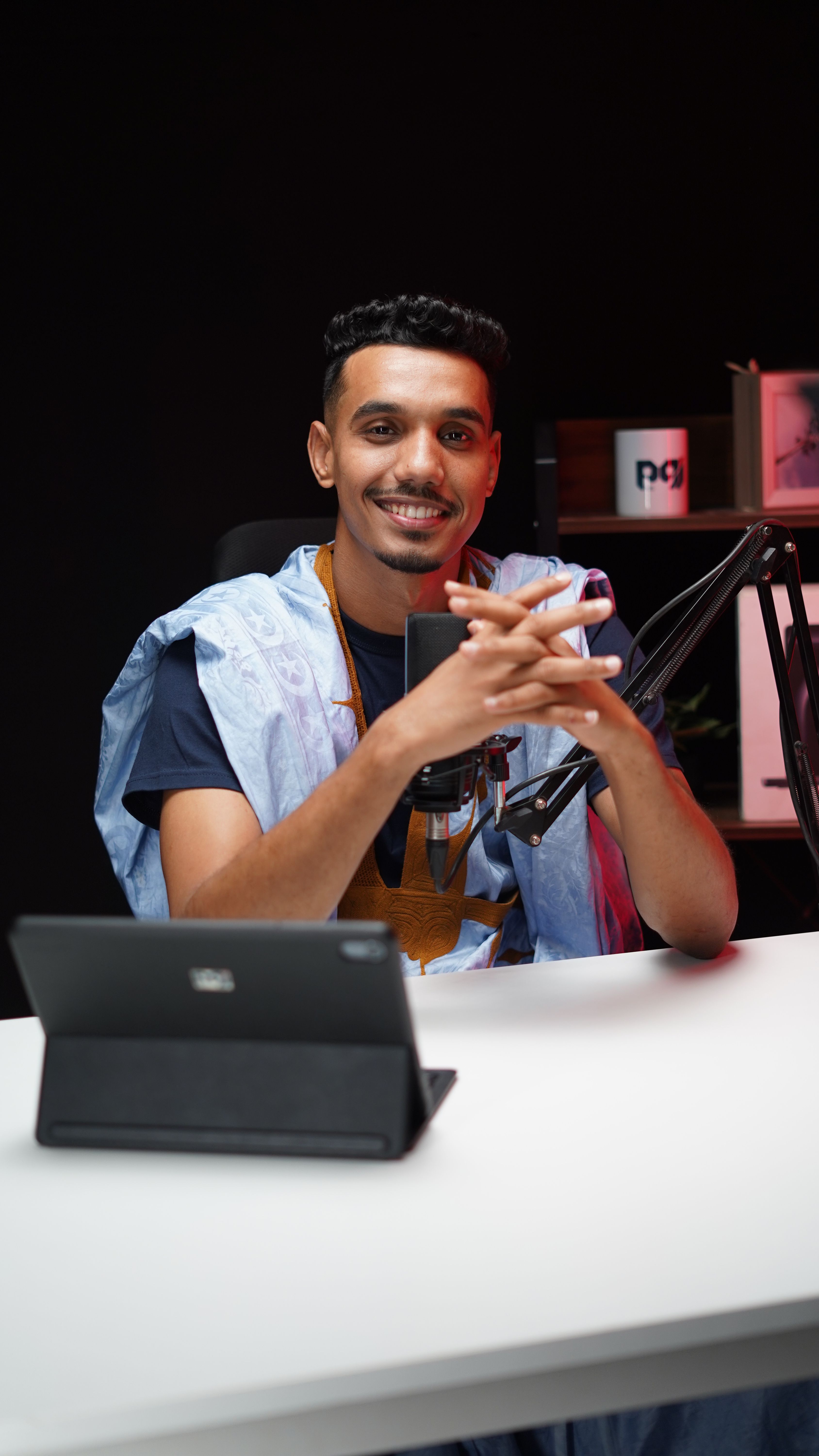 Young adult podcaster smiling during a recording session in a professional studio. Energetic and engaging atmosphere.
