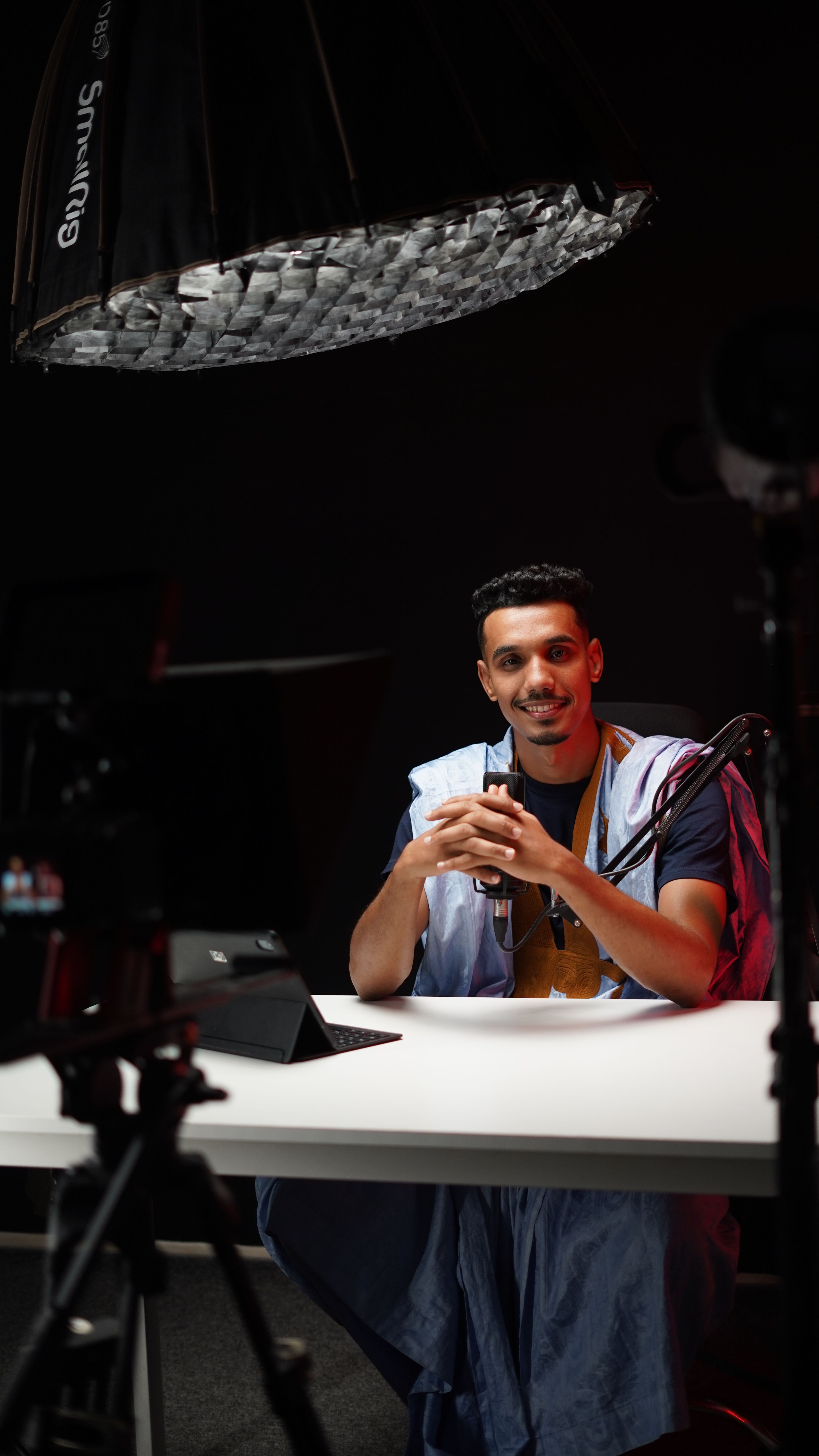 A young man sits confidently in a professional studio setup, surrounded by modern equipment.