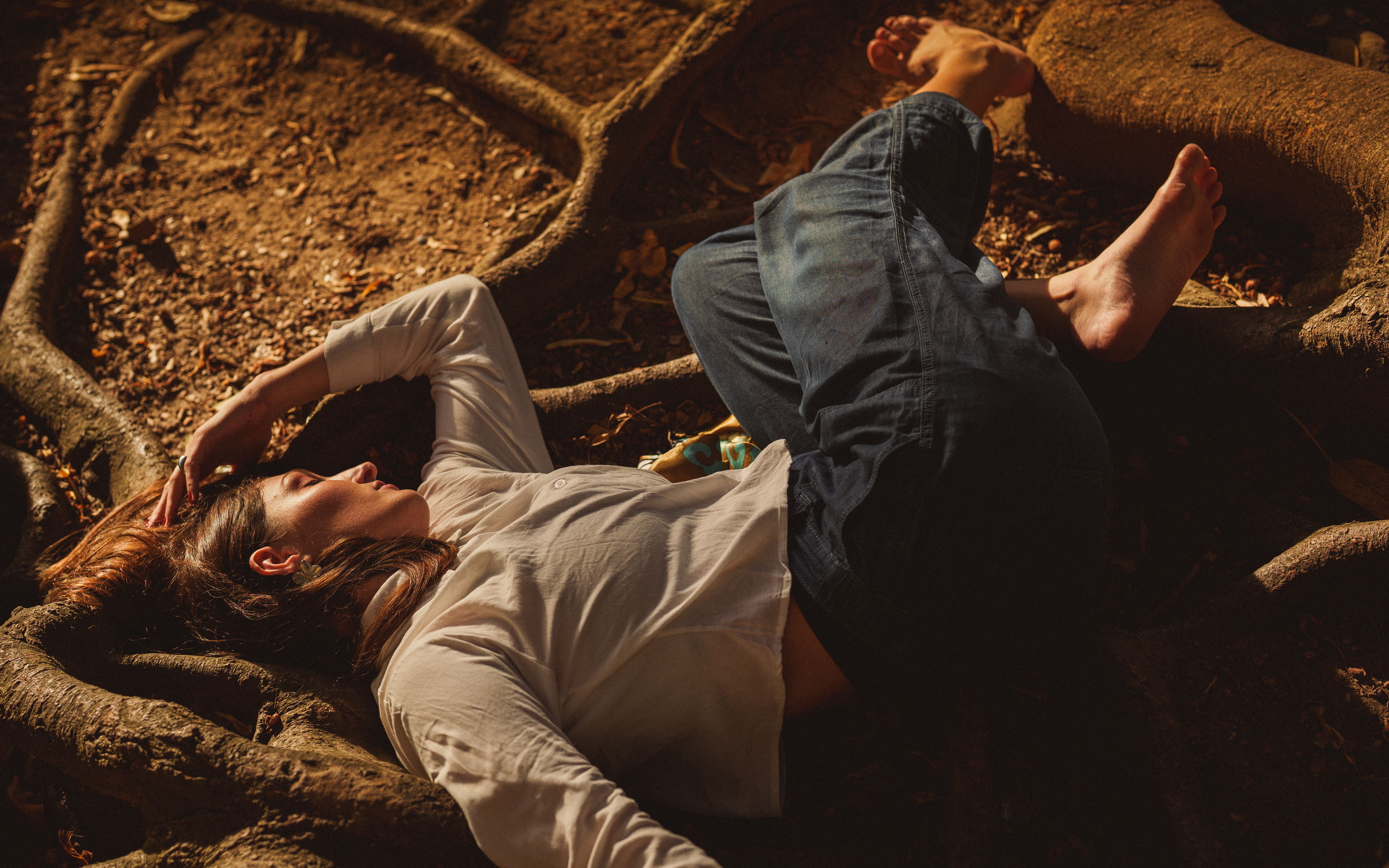 Person calmly resting on tree roots in a sunlit forest setting