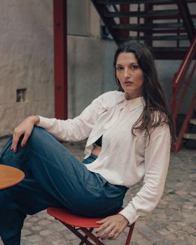 Woman in casual attire sitting outdoors, showcasing a relaxed, contemplative expression.