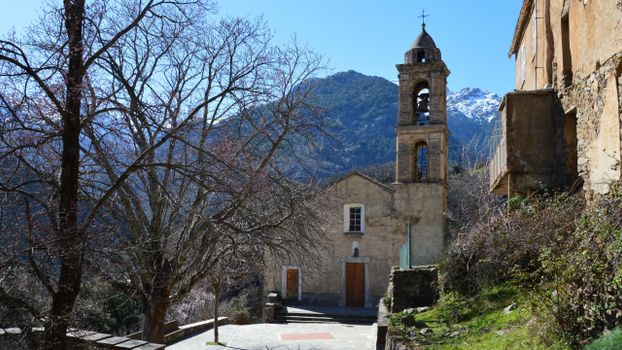 Stone church and bell tower nestled in the scenic mountains of Asco, Corsica.