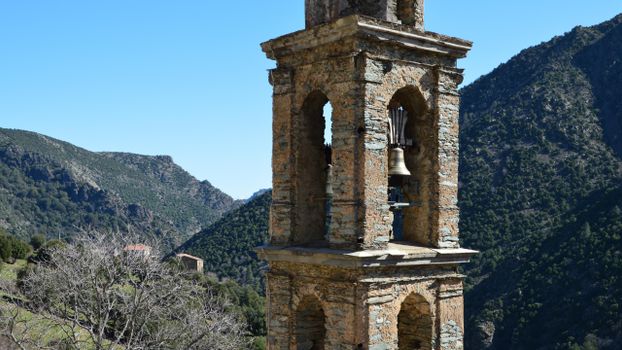 Rustic bell tower in Asco, Corse, France with scenic mountain backdrop.