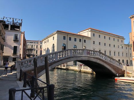Scenic view of a historic bridge over a canal in Venice, Italy on a sunny day.