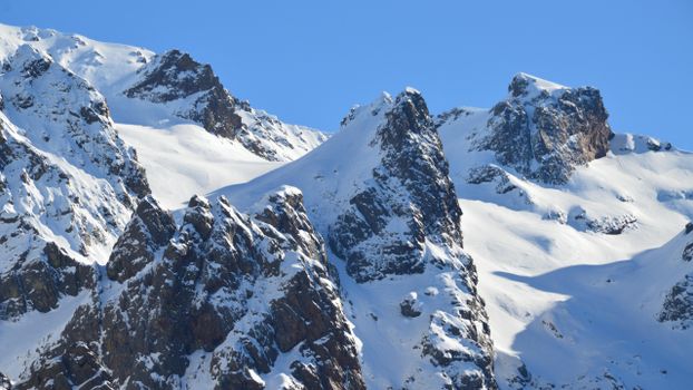 Stunning snow-covered peaks in Asco, Corsica, under a clear blue sky.