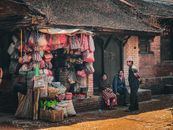Charming street market with locals chatting outside a rustic store in a rural setting.