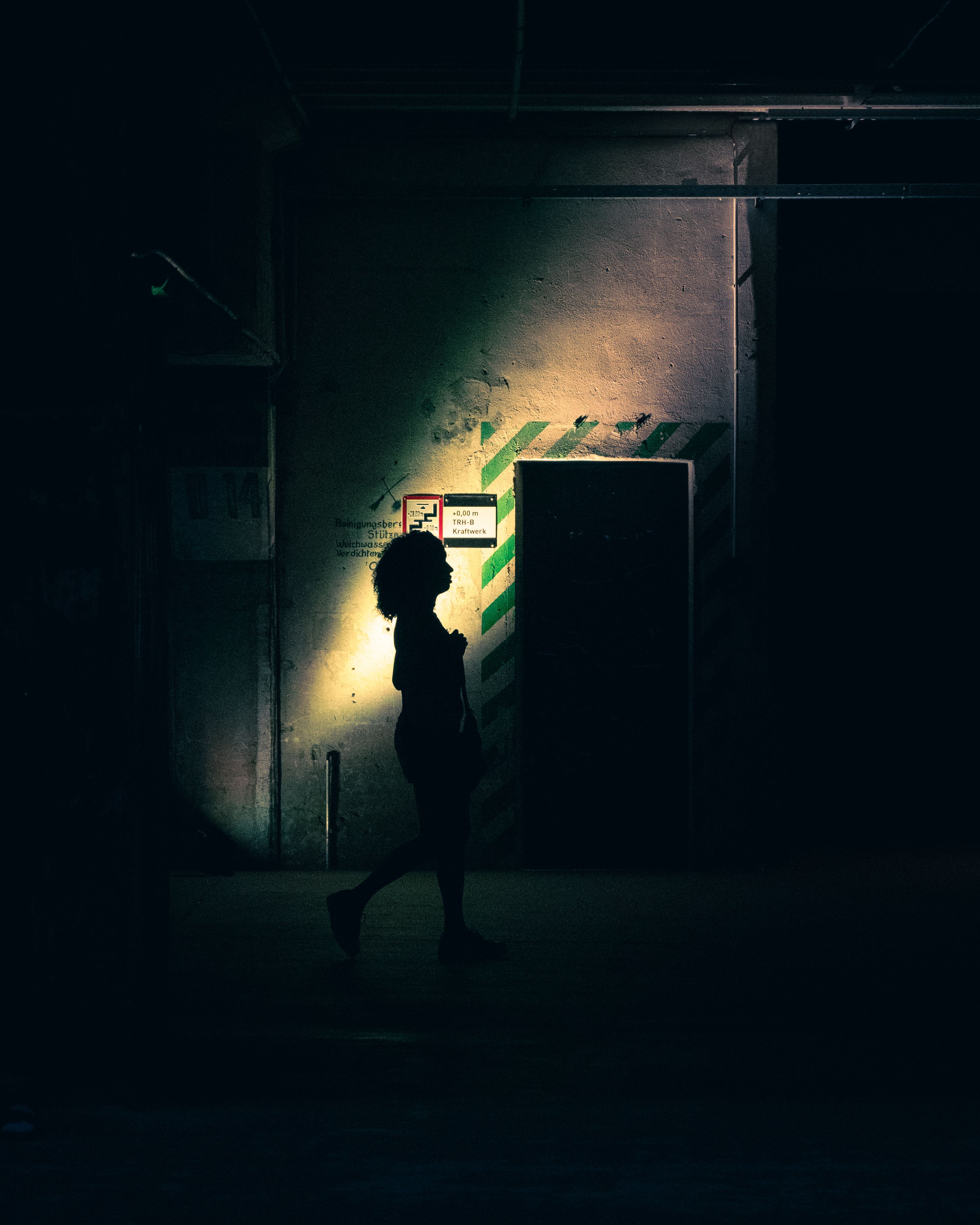 Silhouette of a person walking in a dimly lit industrial space, Berlin.