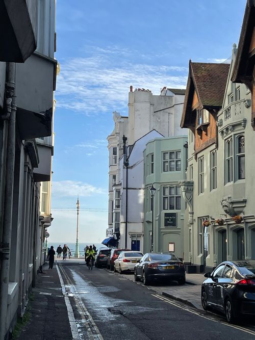 Free A picturesque street in Brighton, UK, featuring charming old architecture and a glimpse of the sea. Stock Photo