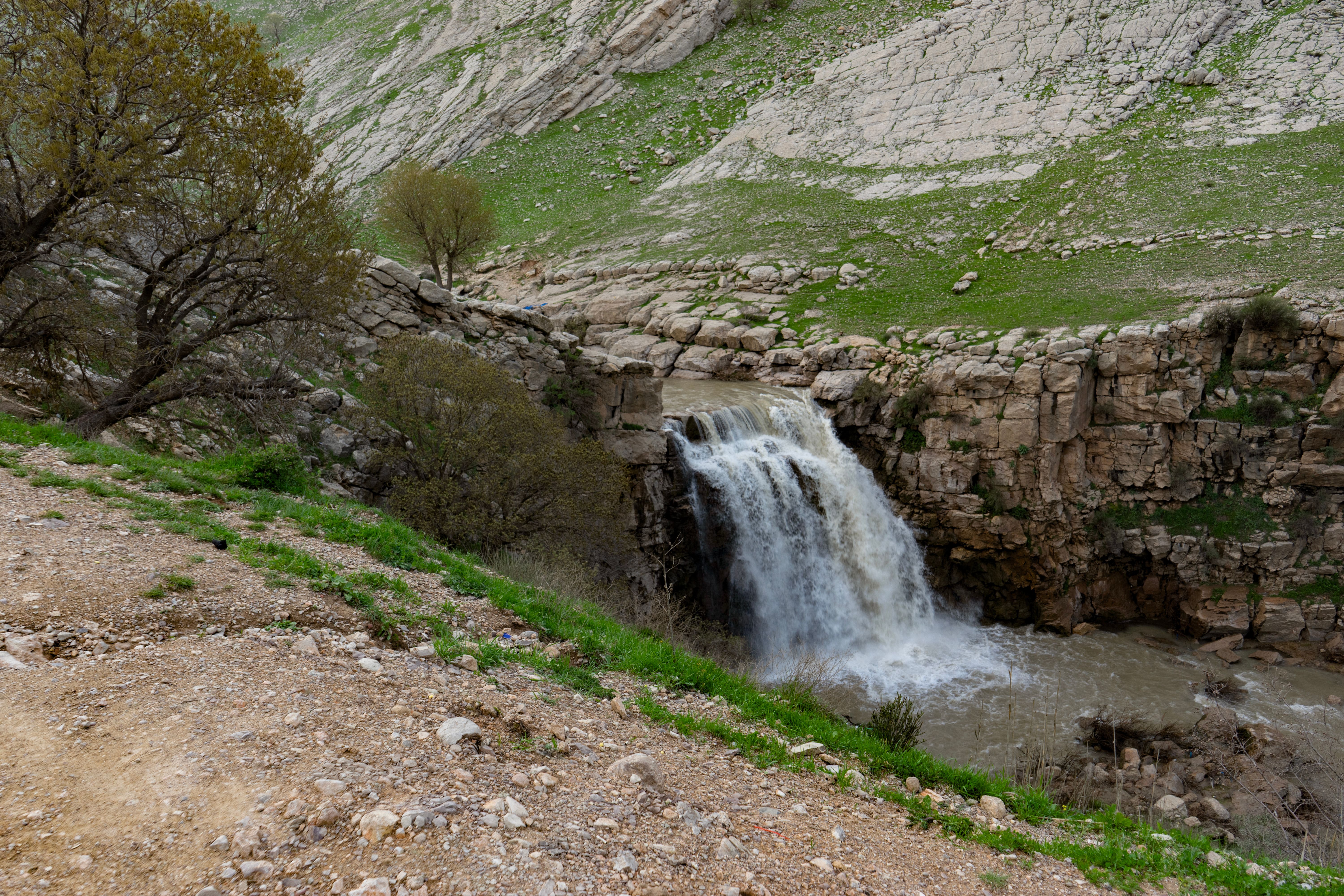 A beautiful waterfall cascades down rocky cliffs surrounded by lush greenery.