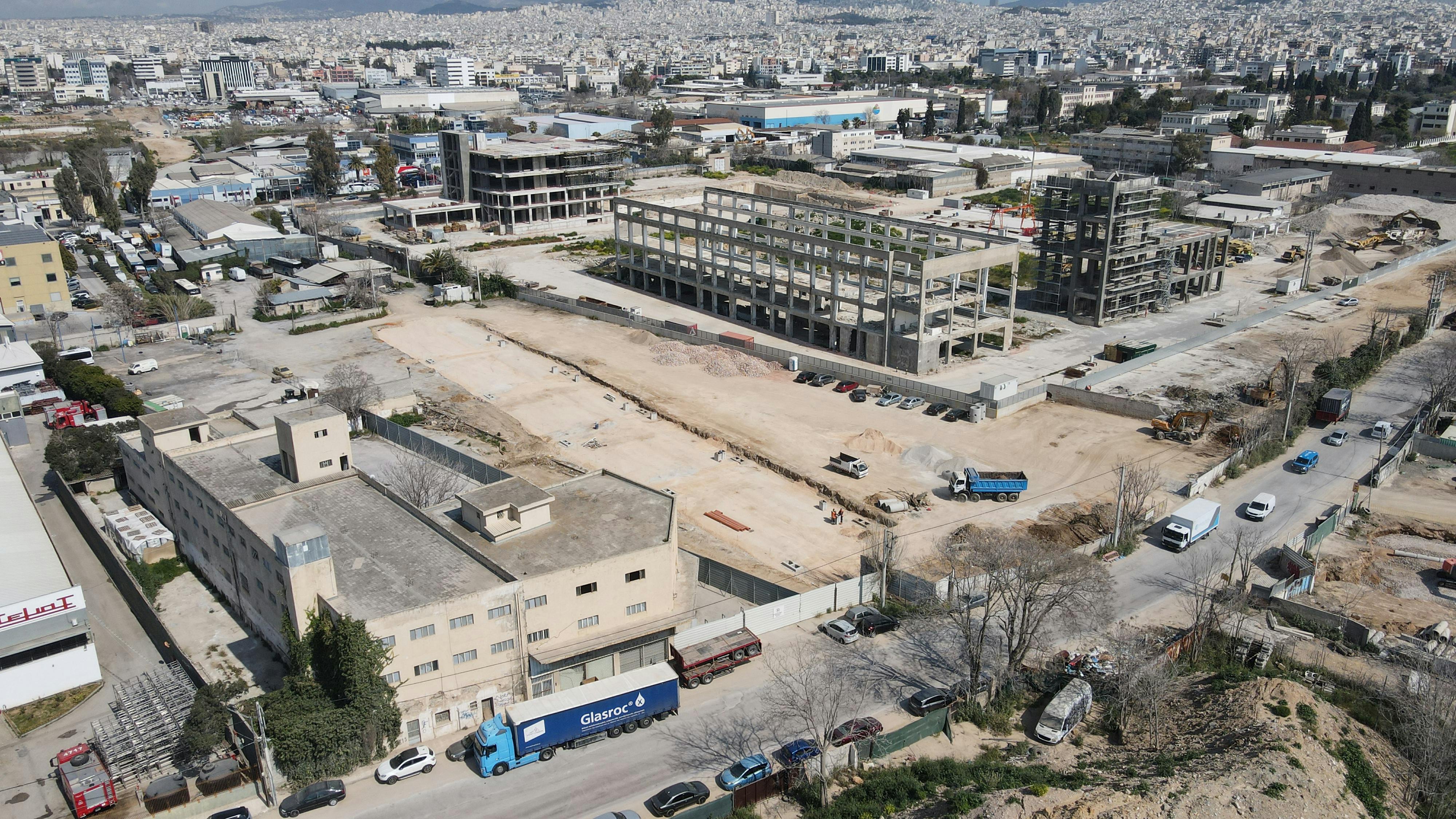 Aerial view of industrial construction site in Athens, showcasing cranes and unfinished buildings.