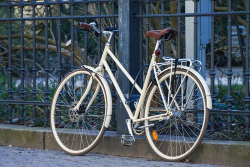 Free Classic cream bicycle leaning against a metal fence in a quiet outdoor setting in Gothenburg, Sweden. Stock Photo