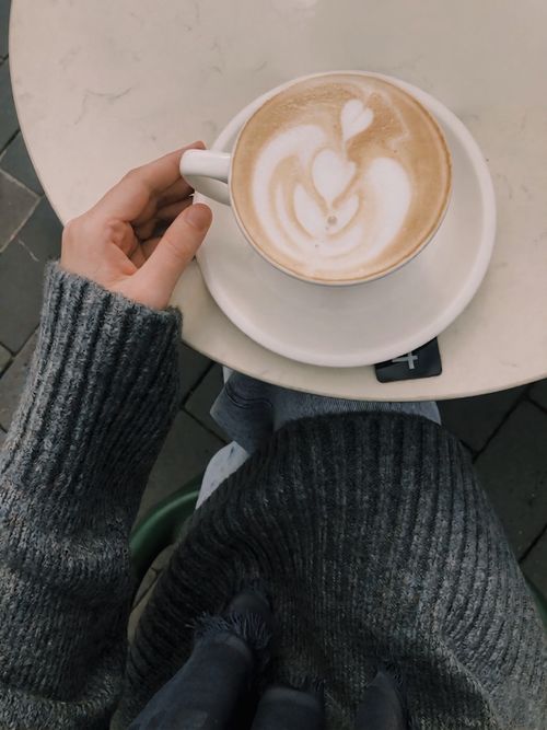 Free A cozy moment captured as a person holds a latte with beautiful latte art. Stock Photo