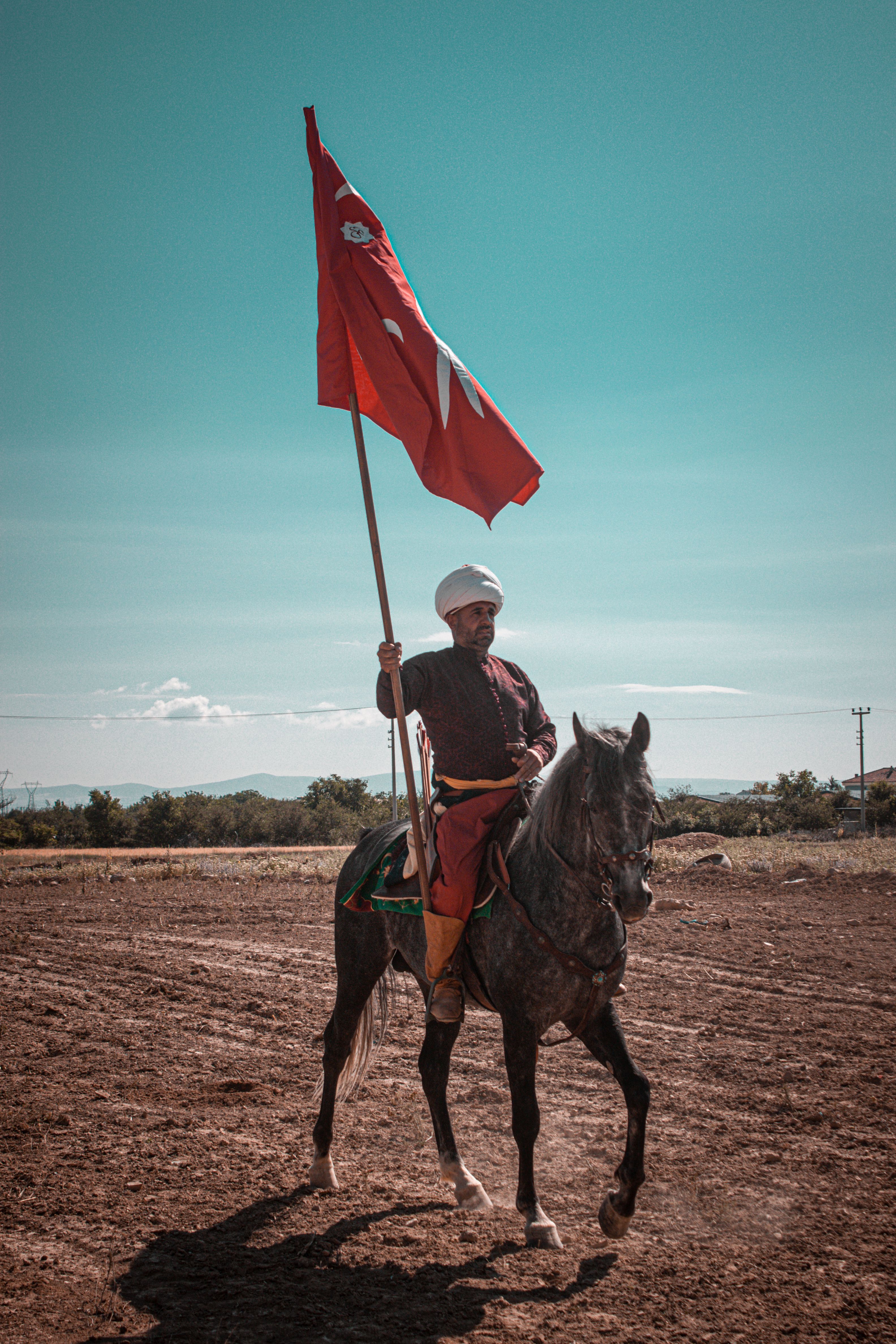 Traditional Turkish horseman carries a flag in Konya, Türkiye, showcasing cultural heritage.