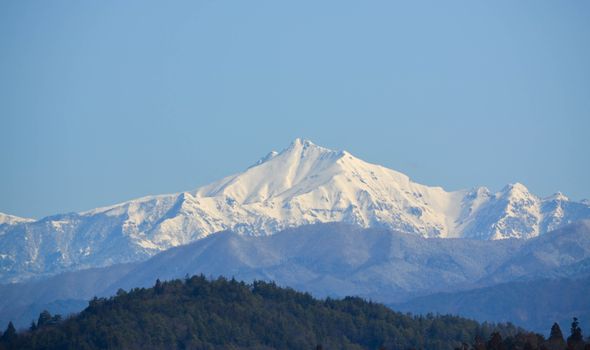 Majestic snow-covered mountain peak under a clear blue sky, perfect for winter travel themes.