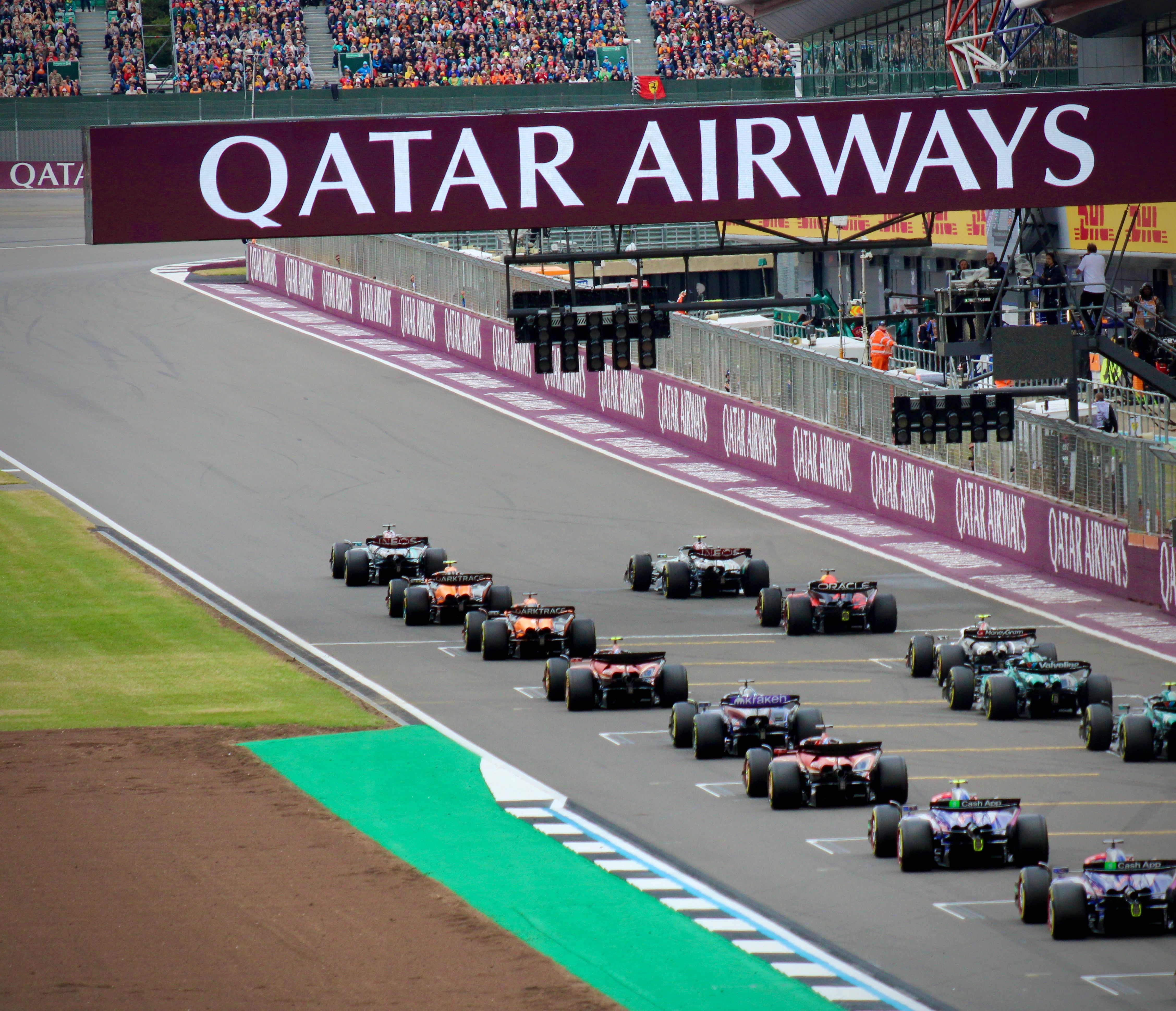 High-speed Formula 1 cars line up on the Silverstone Circuit, ready for an adrenaline-pumping race.