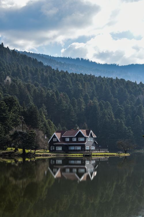 Free Charming house by the lake in Gölcük Köy, surrounded by lush forest and reflected in serene waters. Stock Photo