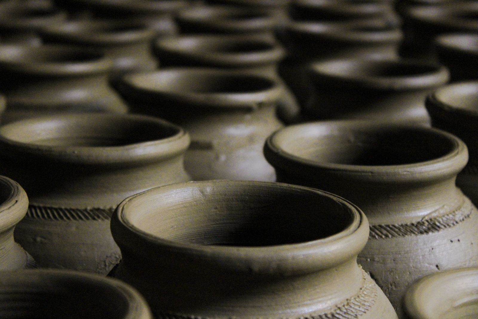 Rows of handcrafted clay pots in a repeating textured pattern