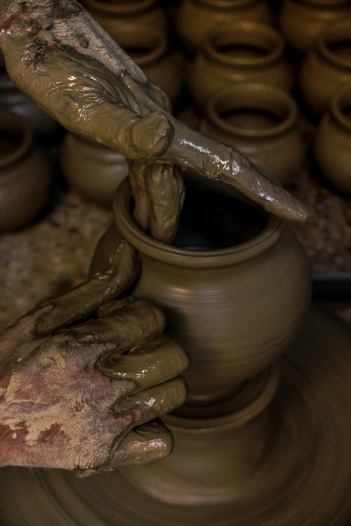 茶色の土鍋を成形する人