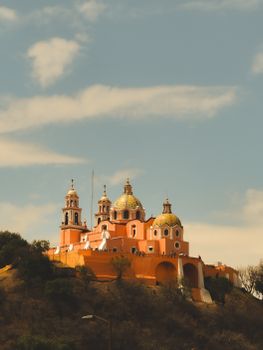 Elevated view of the Sanctuary of Our Lady of Remedies in San Pedro Cholula, Mexico under a clear blue sky.