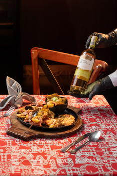 A vibrant Colombian seafood dish accompanied by a serving of white wine in a restaurant setting.