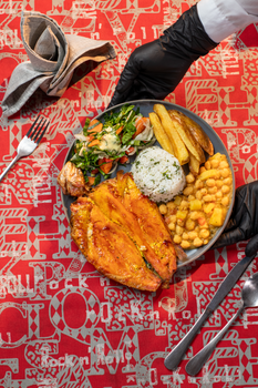 Grilled fish served with rice, potatoes, beans, and fresh salad on a vibrant table.