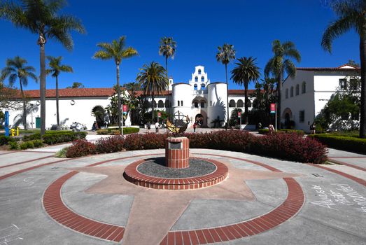 Sunny day at a historic university with palm trees and compass in the courtyard.