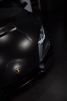 Top view of a sleek black luxury sports car in a modern showroom setting.