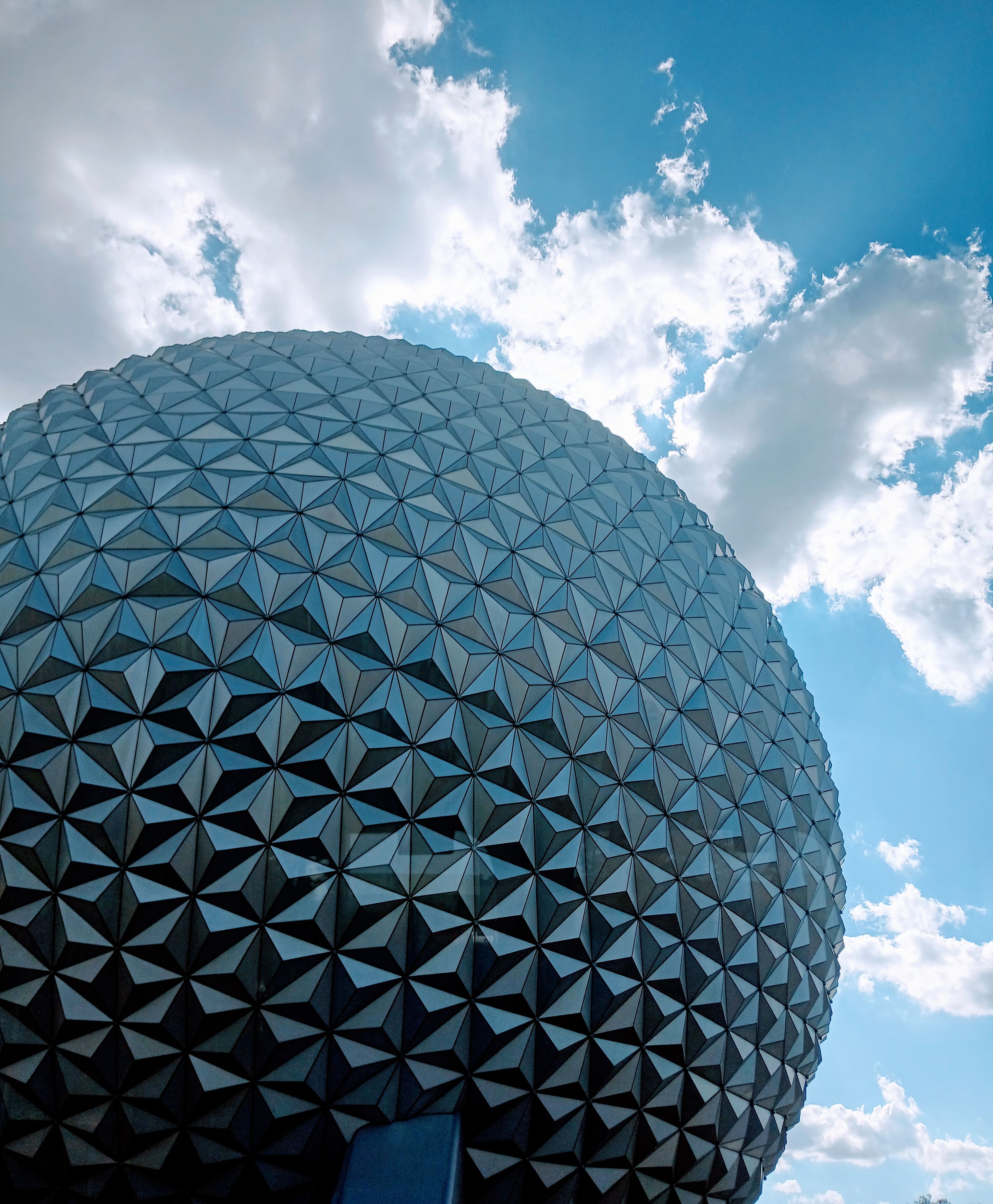 Stunning view of a geodesic dome structure under a clear blue sky with fluffy clouds.