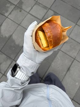 Overhead shot of a person holding a butter bun, showcasing casual street food lifestyle.