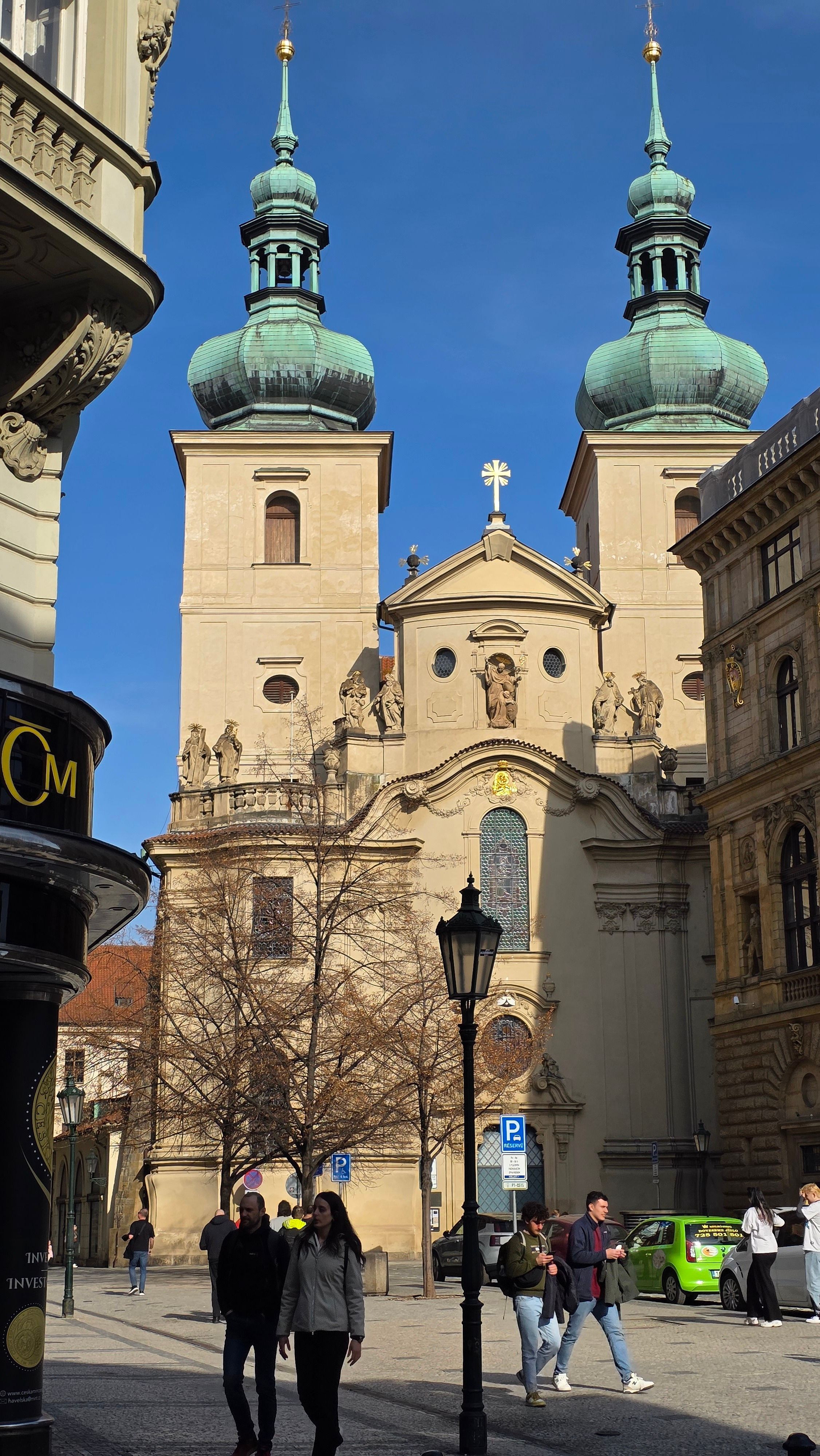 Charming street view of St. James Basilica, Prague with clear blue sky.