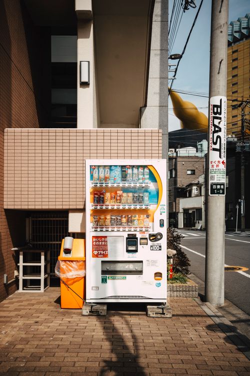 Free A colorful vending machine on a sunny Tokyo street, showcasing Japan's urban landscape. Stock Photo