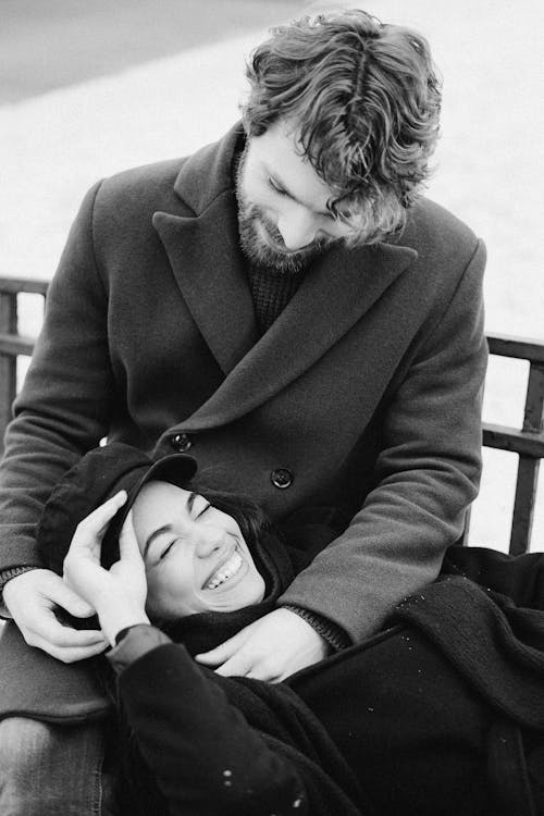 웃는 동안 남자의 무릎에 누워 여자의 흑백 사진