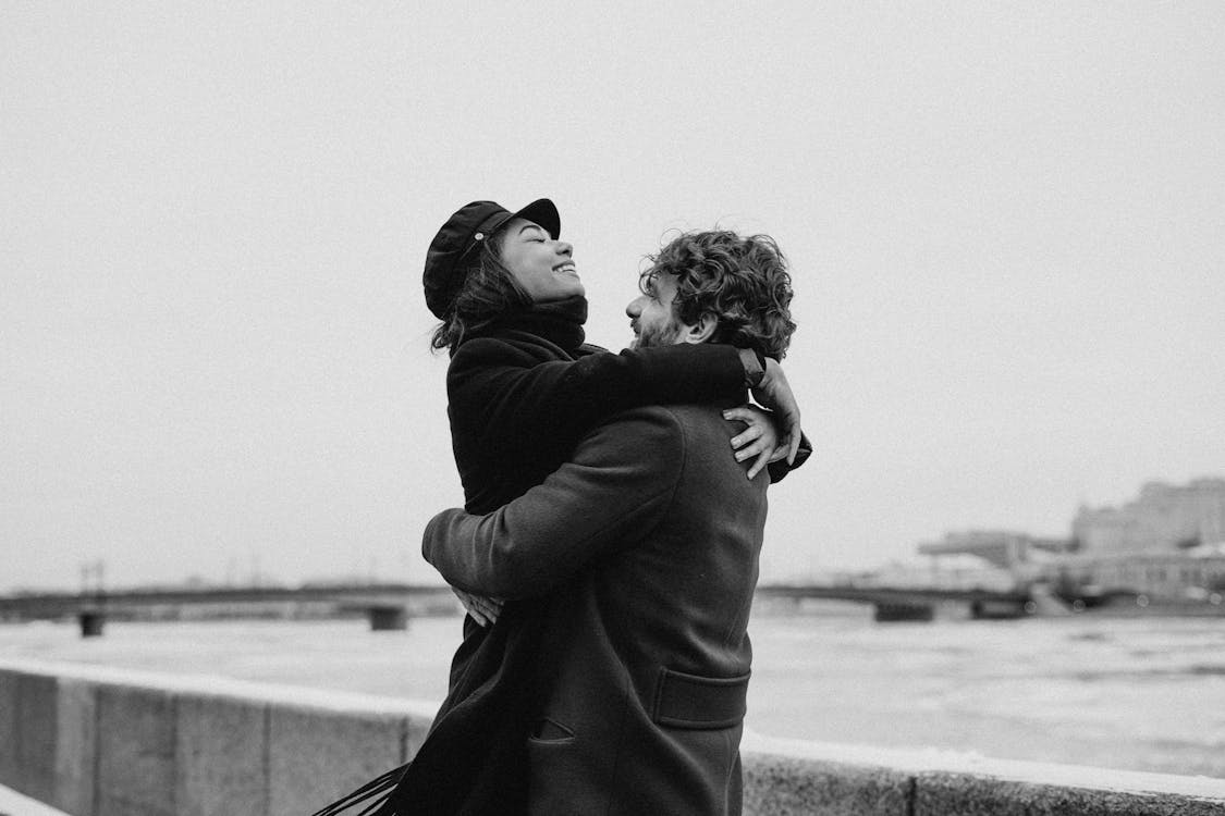 Monochrome Photo of Man Hugging His Woman