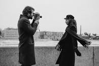 一对夫妇穿着冬装，用老式相机拍摄黑白照片