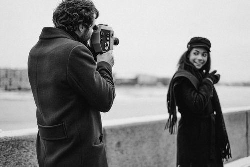 Free A man filming a woman outdoors with a vintage camera in monochrome style. Stock Photo