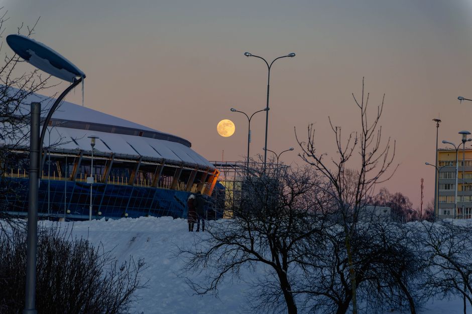 A serene winter scene in Minsk featuring a full moon over snowy landscapes and modern architecture.